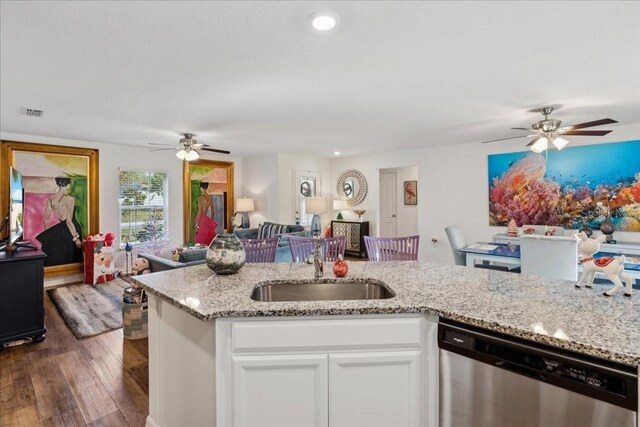 kitchen featuring light stone countertops, stainless steel dishwasher, dark wood-type flooring, sink, and white cabinets