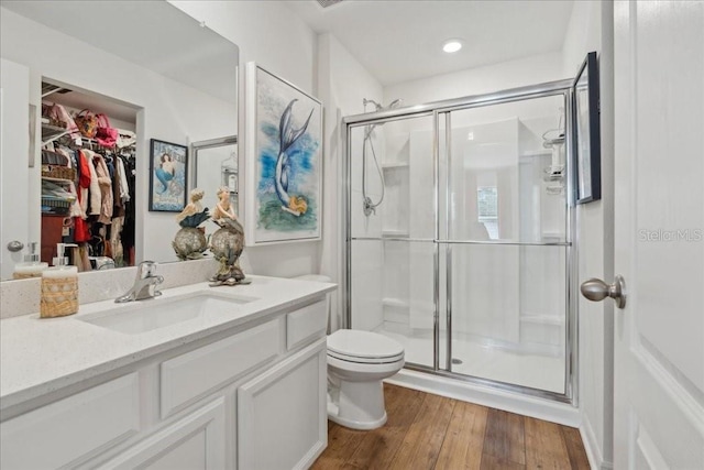 bathroom featuring hardwood / wood-style flooring, vanity, toilet, and a shower with door