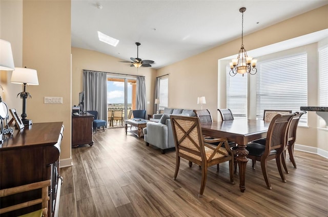 dining space with ceiling fan with notable chandelier, vaulted ceiling, and dark wood-type flooring