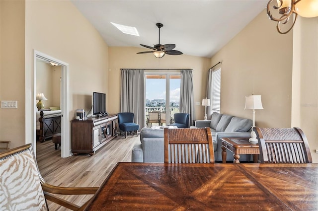 living room with ceiling fan, light hardwood / wood-style flooring, and vaulted ceiling