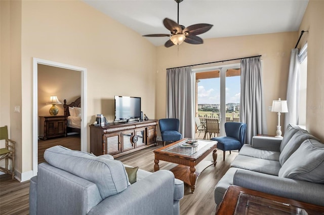 living room with ceiling fan, wood-type flooring, and vaulted ceiling