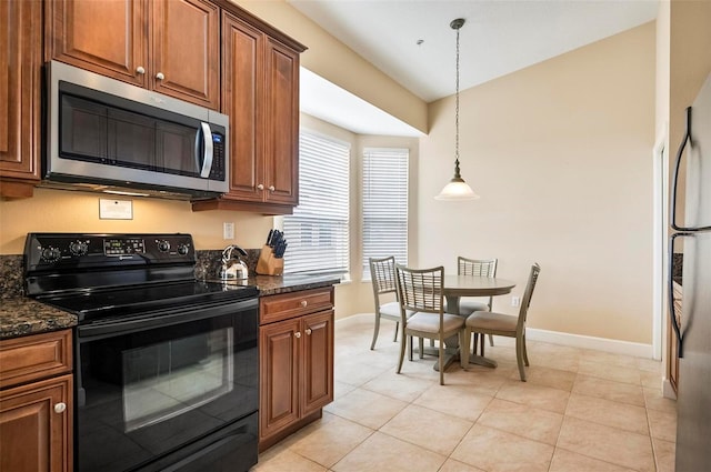 kitchen featuring pendant lighting, light tile patterned flooring, dark stone countertops, and stainless steel appliances