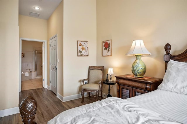 bedroom with ensuite bathroom and dark wood-type flooring