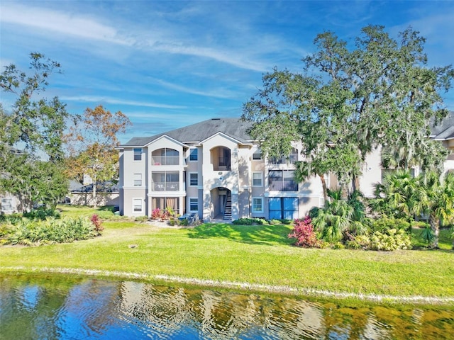 rear view of property featuring a water view and a lawn