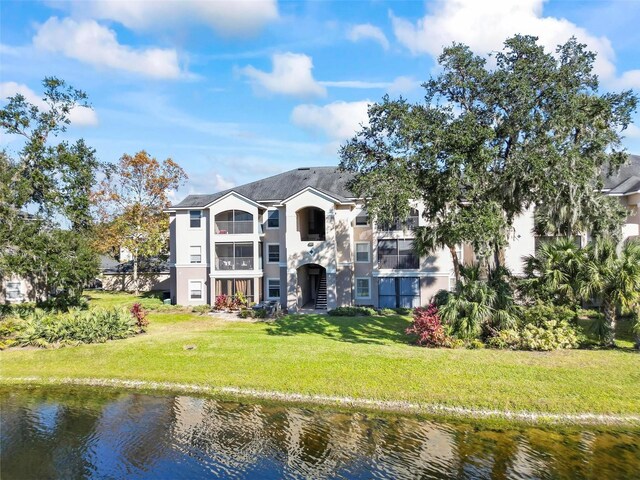 rear view of property featuring a water view and a lawn