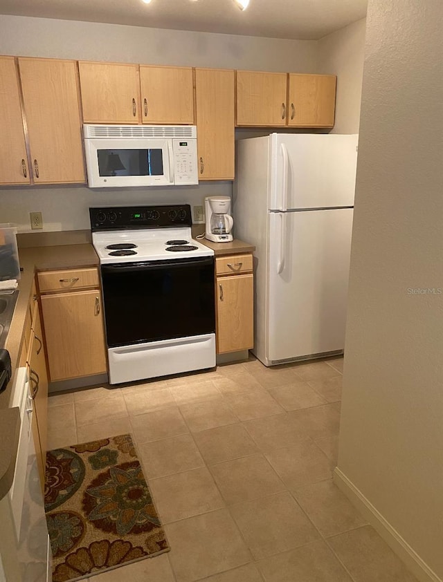 kitchen with light brown cabinets, white appliances, and light tile patterned floors