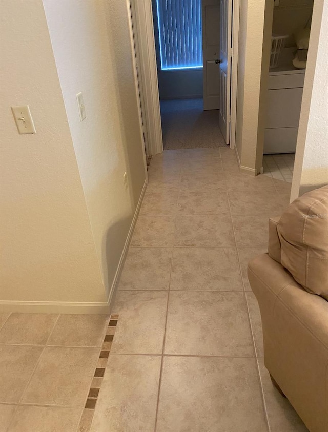 hallway with tile patterned floors and washer / dryer