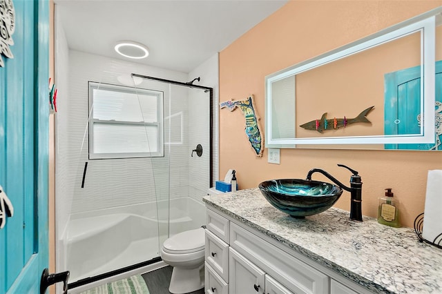 bathroom featuring hardwood / wood-style flooring, vanity, toilet, and a shower with shower door