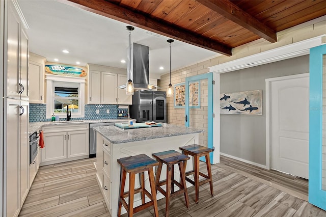 kitchen with stainless steel appliances, extractor fan, white cabinetry, a kitchen island, and hanging light fixtures