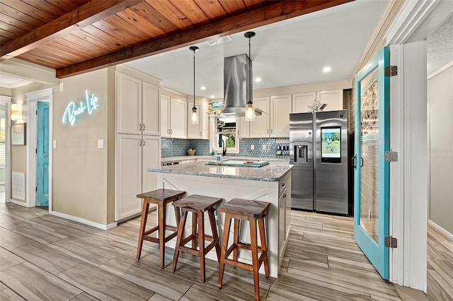 kitchen featuring light wood-type flooring, light stone counters, beam ceiling, stainless steel fridge with ice dispenser, and hanging light fixtures