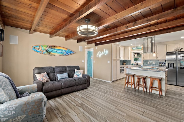 living room with light hardwood / wood-style floors, beam ceiling, and wooden ceiling