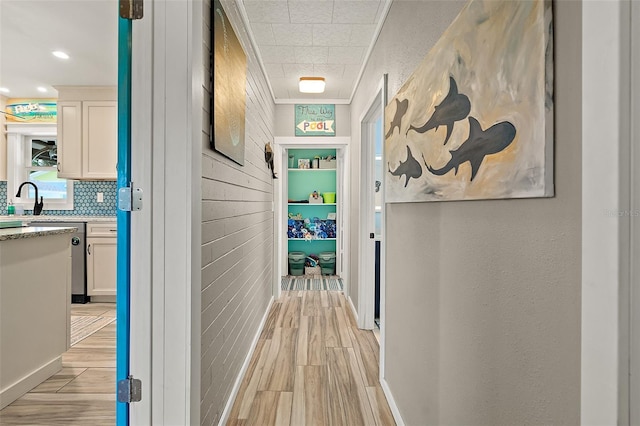 hall with light hardwood / wood-style flooring, crown molding, and sink