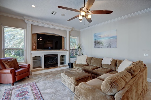 living room featuring a fireplace, ornamental molding, a textured ceiling, and ceiling fan