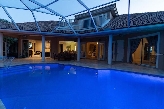 view of swimming pool with ceiling fan, glass enclosure, and a patio area