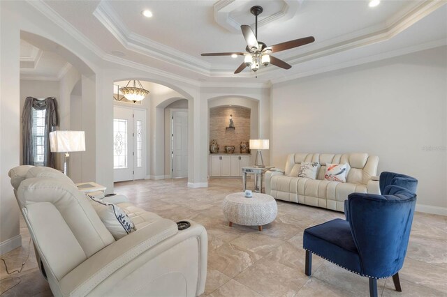 67 Island Estates Pkwy, Palm Coast, FL 32137 - living area featuring arched walkways, a tray ceiling, a ceiling fan, ornamental molding, and baseboards
