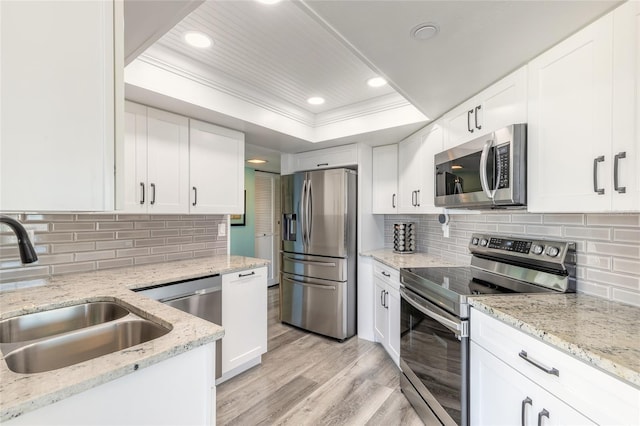 kitchen with white cabinets, stainless steel appliances, and light hardwood / wood-style flooring