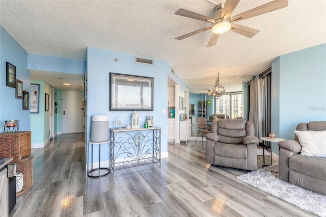 living room with ceiling fan with notable chandelier, a textured ceiling, and hardwood / wood-style flooring