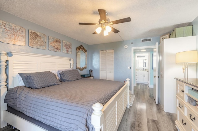 bedroom with a textured ceiling, a closet, ceiling fan, and light hardwood / wood-style floors