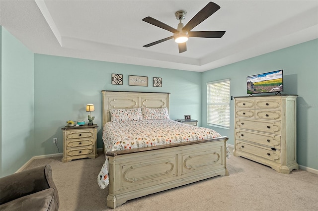 carpeted bedroom featuring a raised ceiling and ceiling fan