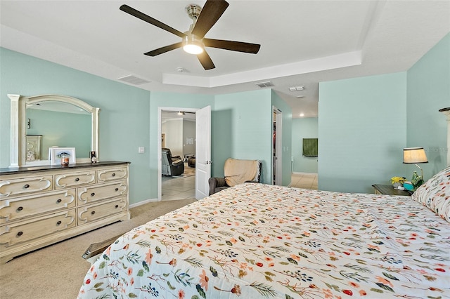 bedroom featuring a raised ceiling, light carpet, and ceiling fan