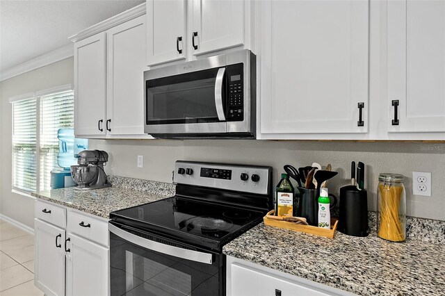 kitchen with light stone countertops, light tile patterned floors, crown molding, white cabinets, and appliances with stainless steel finishes