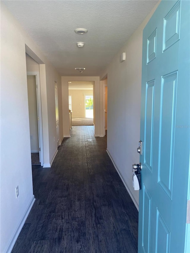 hallway with dark hardwood / wood-style flooring and a textured ceiling