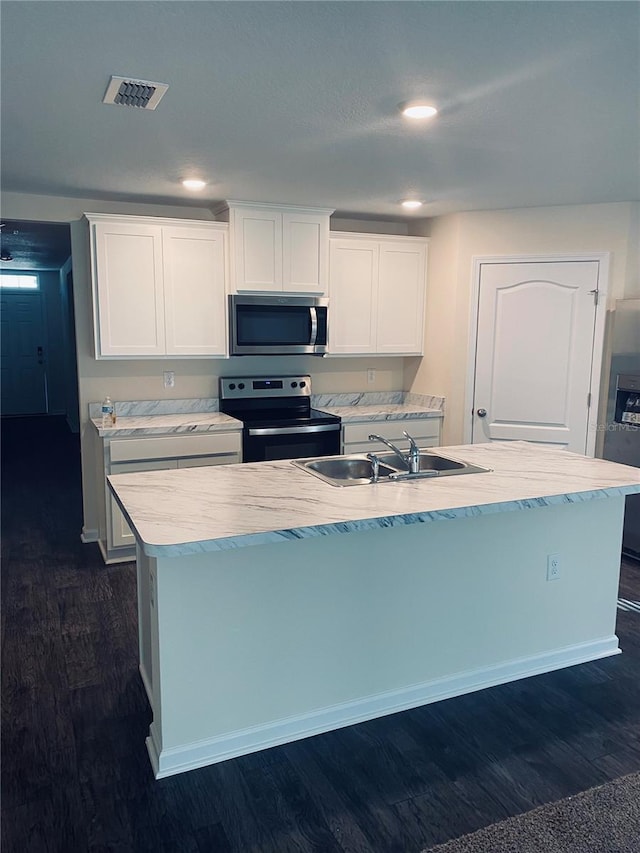 kitchen with sink, dark hardwood / wood-style floors, an island with sink, white cabinets, and appliances with stainless steel finishes