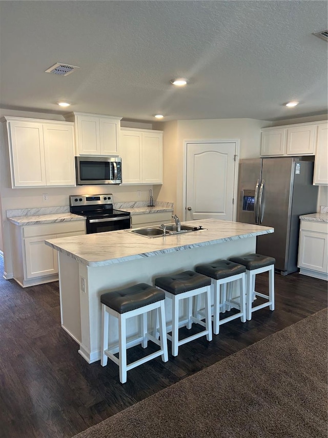 kitchen with white cabinets, a kitchen island with sink, stainless steel appliances, light countertops, and a sink