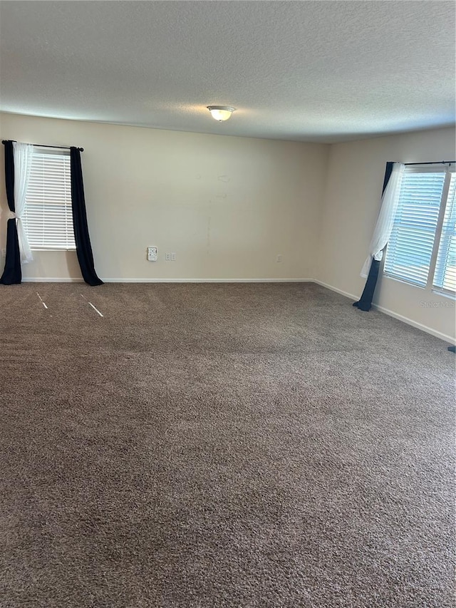 unfurnished room with a textured ceiling, baseboards, and carpet flooring