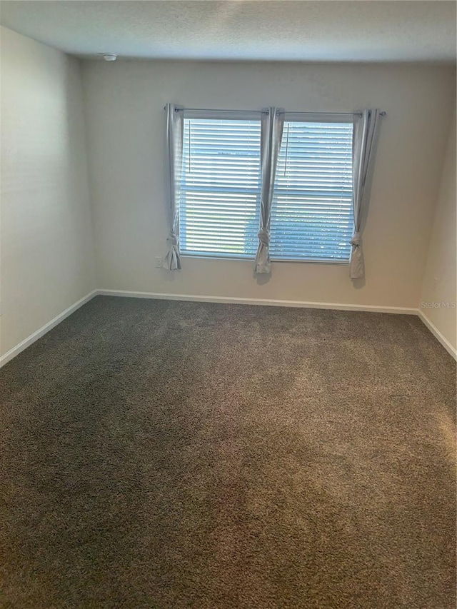 unfurnished room featuring carpet and baseboards