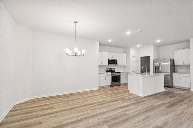 kitchen featuring stainless steel appliances, pendant lighting, light hardwood / wood-style floors, a kitchen island with sink, and white cabinets