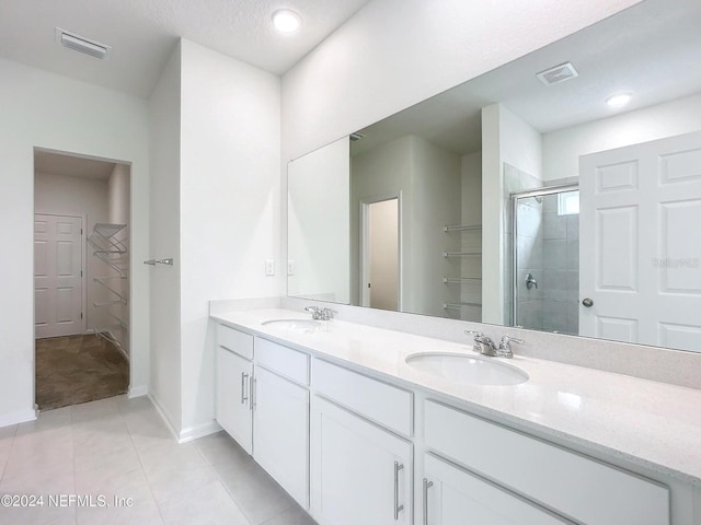 bathroom featuring tile patterned floors, a shower with door, vanity, and a textured ceiling