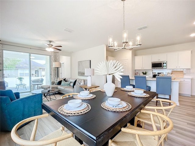 dining space featuring light hardwood / wood-style flooring and ceiling fan with notable chandelier