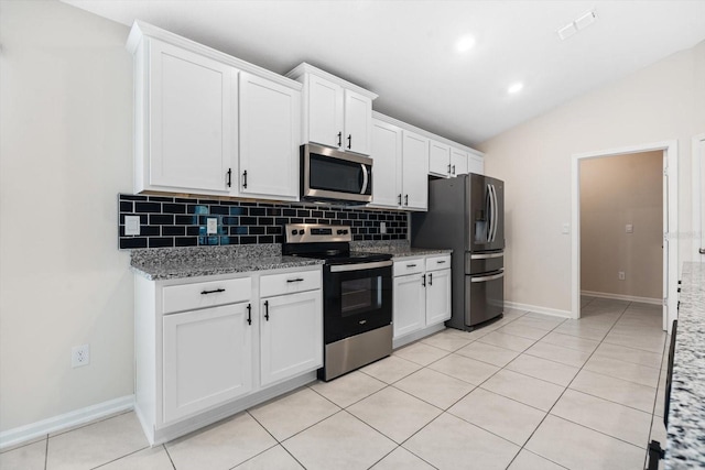 kitchen featuring light stone counters, backsplash, lofted ceiling, white cabinets, and appliances with stainless steel finishes