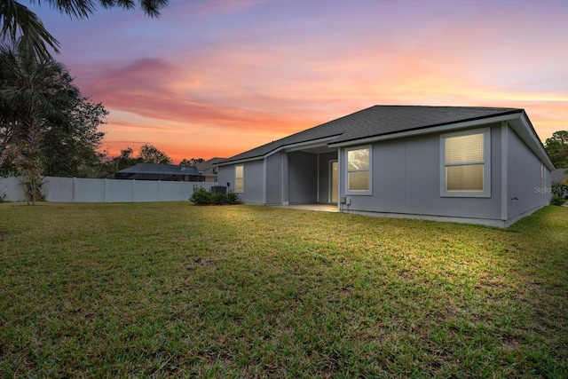 back house at dusk featuring a yard