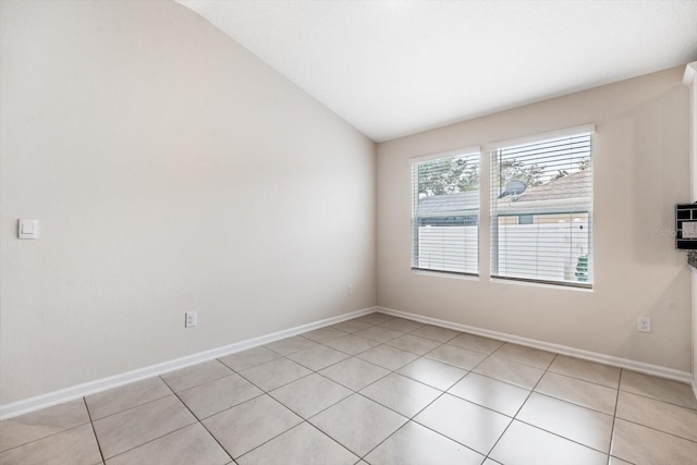 tiled spare room featuring vaulted ceiling