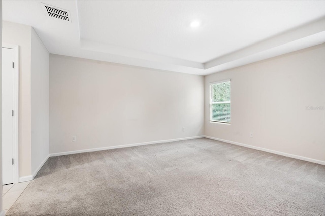 carpeted spare room with a raised ceiling