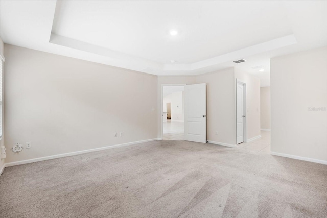 spare room with a raised ceiling and light carpet