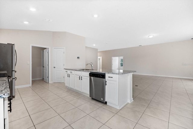 kitchen featuring appliances with stainless steel finishes, light stone counters, a center island with sink, white cabinetry, and lofted ceiling