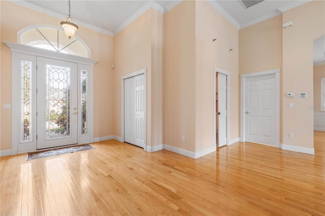 foyer with light wood-type flooring, crown molding, and a high ceiling