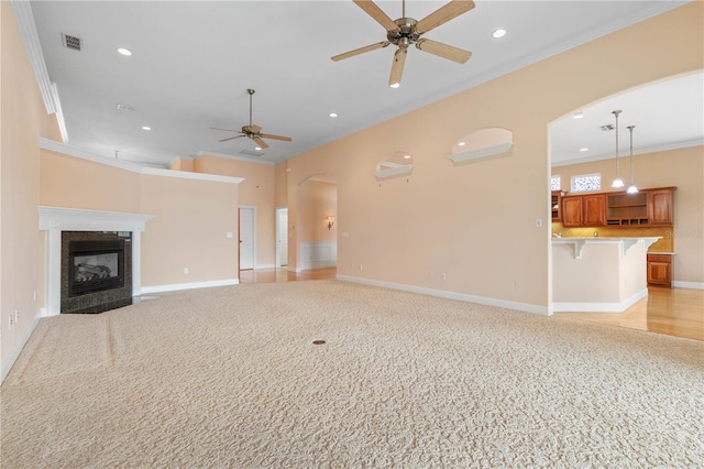 unfurnished living room featuring light carpet, a fireplace, ceiling fan, and ornamental molding