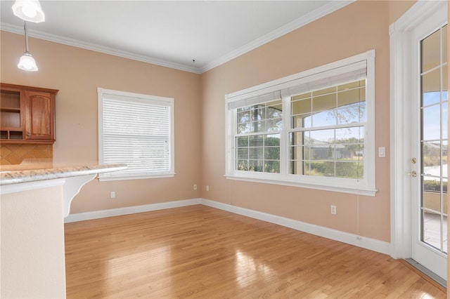 unfurnished dining area featuring light hardwood / wood-style floors and crown molding