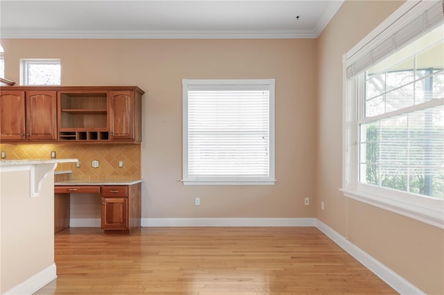 kitchen featuring built in desk, backsplash, light hardwood / wood-style flooring, and crown molding