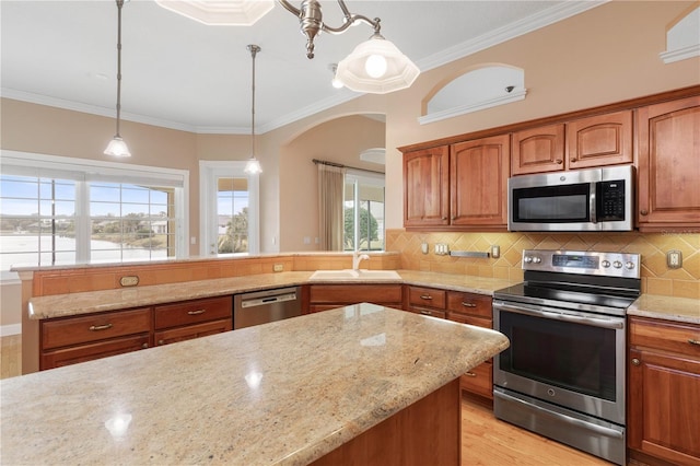 kitchen with hanging light fixtures, crown molding, sink, light stone countertops, and appliances with stainless steel finishes