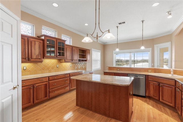 kitchen featuring dishwasher, hanging light fixtures, a kitchen island, ornamental molding, and light hardwood / wood-style floors