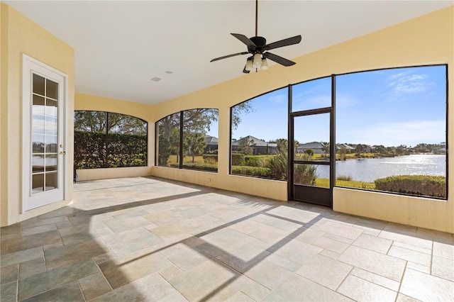 unfurnished sunroom with ceiling fan and a water view