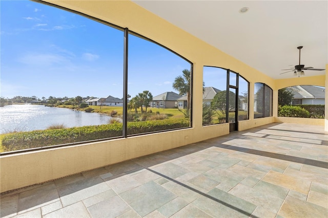 unfurnished sunroom featuring a water view and ceiling fan