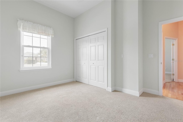 unfurnished bedroom with light carpet and a closet