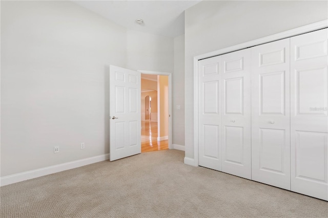 unfurnished bedroom with a closet and light colored carpet