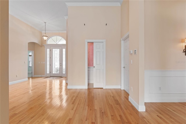 entrance foyer featuring light hardwood / wood-style floors, crown molding, and a high ceiling